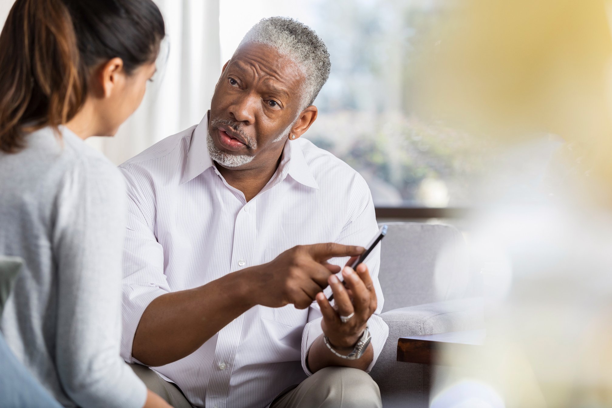 Senior man shows counselor something on smartphone